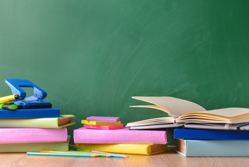 Set of school supplies on table near blackboard