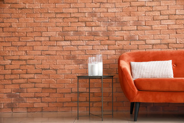 Comfortable sofa and table near brick wall