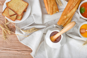 Tasty honey with bread and tea on table