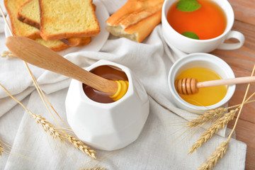 Tasty honey with bread and tea on table