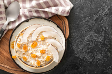Bowl with tasty sweet oatmeal on dark background
