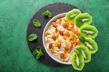 Bowl with tasty sweet oatmeal on color background