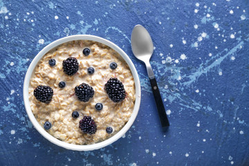 Bowl with tasty sweet oatmeal on color background