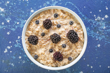 Bowl with tasty sweet oatmeal on color background