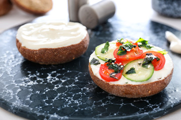 Fresh bun with tasty cream cheese and vegetables on table