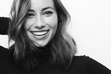 Black and white portrait of young happy woman with a big smile on her face looking in camera