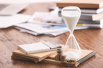 Hourglass, notebooks, calculator and coins on table. Time management concept