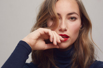 Portrait of a young beautiful woman with red lips looking directly and seriously in camera 
