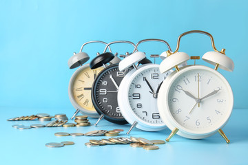 Alarm clocks and coins on color background. Time management concept