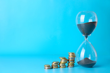 Hourglass and coins on color background. Time management concept