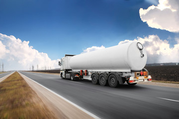 Big fuel tanker truck shipping fuel on the countryside road in motion against sky - 330594043