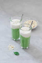 Green spinach smoothie with oatmeal smoothie in a glass on a light background