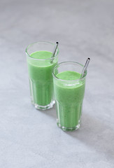 Spinach smoothie cocktail in a glass on a light gray background