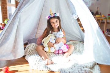 Adorable toddler sitting on the floor inside tipi around lots of toys at kindergarten © Krakenimages.com