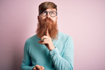 Handsome Irish redhead man with beard wearing glasses over pink isolated background Thinking...