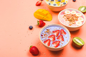 Beautiful multi-colored healthy smoothie bowls with berries and superfoods on a bright background. Summer food for detox concept. Background with copyspace.