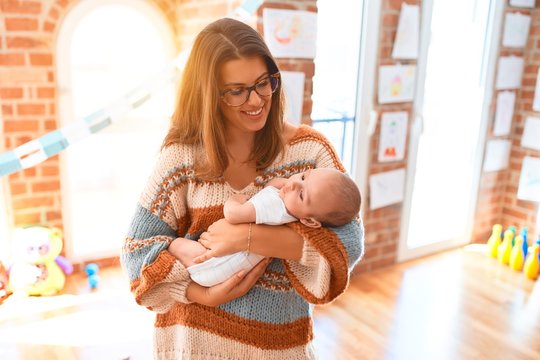 Young beautiful woman and her baby standing at home. Mother holding and hugging newborn