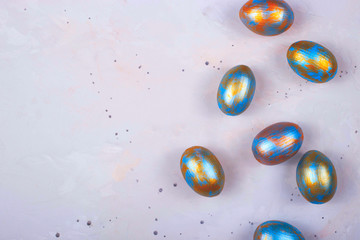 Colored Easter eggs in blue and gold lie on gray background. Minimalistic holiday layout. Top view, copy space.