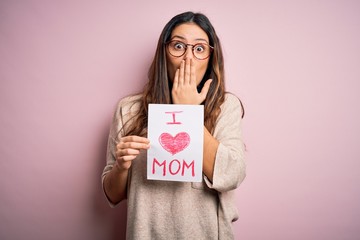 Young beautiful woman holding paper with love mom message celebrating mothers day cover mouth with hand shocked with shame for mistake, expression of fear, scared in silence, secret concept