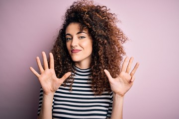 Young beautiful woman with curly hair and piercing wearing casual striped t-shirt showing and...