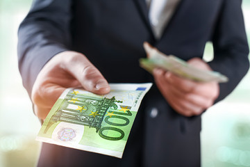 Business Man give a spread of euros cash over bank background. Euro currency detail. Money...