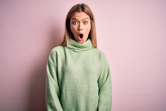 Young beautiful blonde woman wearing winter wool sweater over pink isolated background afraid and shocked with surprise expression, fear and excited face.