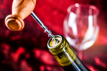 Opening wine bottle with corks crew with red on the background