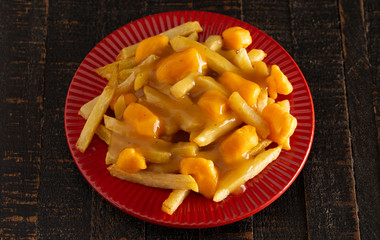 Plate of Poutine with Orange Cheddar Cheese with Brown Gravy on French Fries
