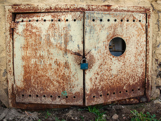 Tin door, rusted and scrusted with padlock