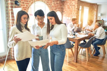Beautiful businesswomen smiling happy. Standing with smile on face working together reading documents using smartphone at the office
