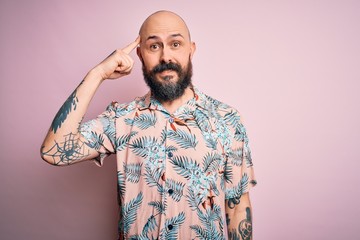 Handsome bald man with beard and tattoo wearing casual floral shirt over pink background Smiling pointing to head with one finger, great idea or thought, good memory