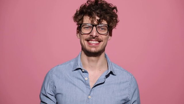 attractive casual man wearing glasses standing and laughing happy then shaking his head on pink studio background