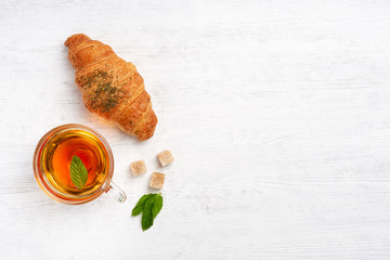   Croissant with zaatar  and cup  of tea on white wooden table. Top view