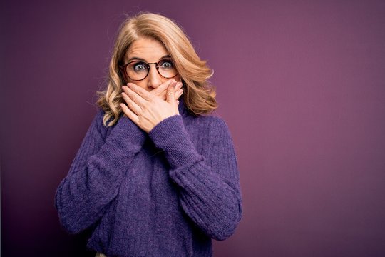 Middle age beautiful blonde woman wearing casual purple turtleneck sweater and glasses shocked covering mouth with hands for mistake. Secret concept.