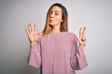 Young beautiful blonde woman with blue eyes wearing stiped t-shirt over white background showing...