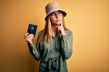 Blonde tourist woman with blue eyes on vacation holding australian passport using binoculars...