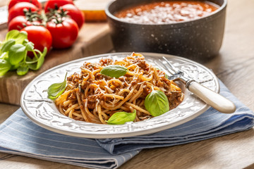 Italian pasta spaghetti bolognese served on white plate with parmesan cheese and basil