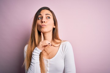 Young beautiful blonde woman with blue eyes wearing white t-shirt over pink background Thinking...