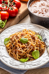 Italian pasta spaghetti bolognese served on white plate with parmesan cheese and basil