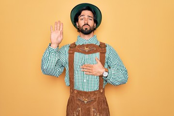 Young handsome man wearing tratidional german octoberfest custome for Germany festival Swearing...