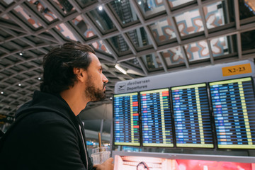 A man near the schedule board at the airport.