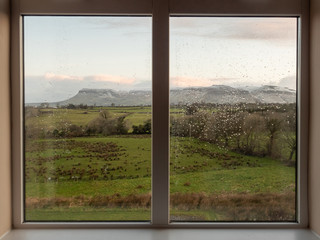 Window in a house with beautiful scenery with green fields and mountains. Concept high end accommodation.