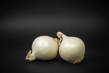 Garlic onion on a dark black background. The concept of food and cooking. Eating vegetables and healthy nutrition. Eating white onions, adding to dishes.