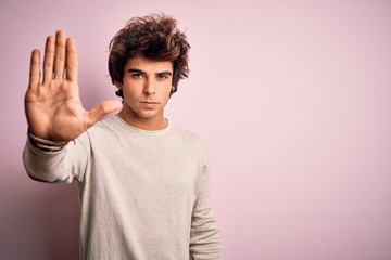 Young handsome man wearing casual t-shirt standing over isolated pink background doing stop sing...