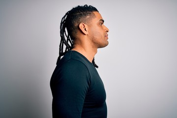 Young handsome african american man with dreadlocks wearing black casual sweater looking to side, relax profile pose with natural face with confident smile.