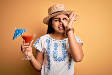 Young asian girl on vacation wearing summer hat drinking cocktail over yellow background with happy...