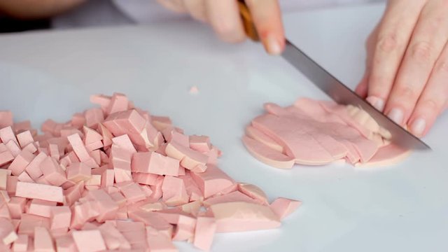 Man cuts cooked sausage mortadella