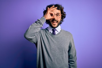 Handsome businessman with beard wearing tie and glasses standing over purple background doing ok gesture with hand smiling, eye looking through fingers with happy face.