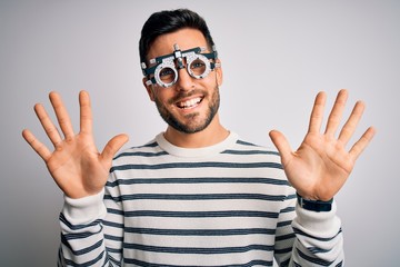 Naklejka premium Young handsome man with beard wearing optometry glasses over isolated white background showing and pointing up with fingers number ten while smiling confident and happy.