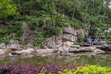 Guilin, China - May 11, 2010: Seven Star Park. Landscape with short waterfall scenery with white streams set in green and red foliage with rocks.